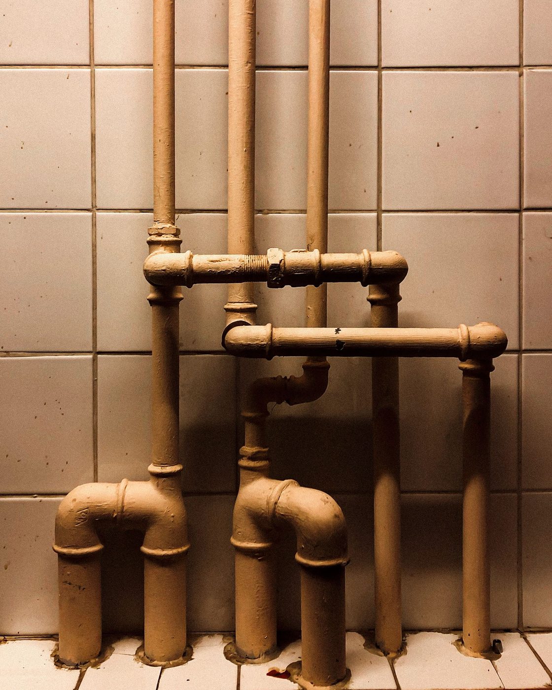 Copper and brass pipework running across a tiled wall